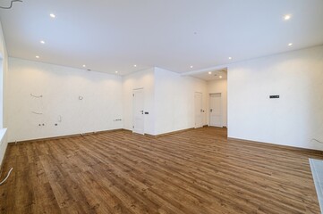 Bright, spacious room with wood floors, white walls, and multiple doors. Appears to be newly...
