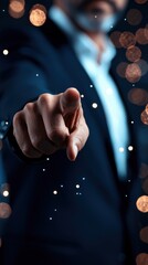 A person in a suit points directly at the camera with blurred background lights creating a bokeh effect.