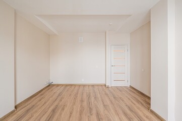 Fototapeta premium Bright, empty room with light beige walls, wood-look flooring, and a white door. Clean and modern