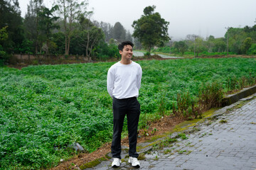man standing casual outdoors in rural green field on a cloudy day