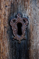 Close-up of a rusty keyhole on a wooden door