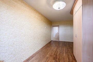 cozy room with patterned wallpaper, a wooden floor, and a wardrobe. A glass-paneled door leads to another room