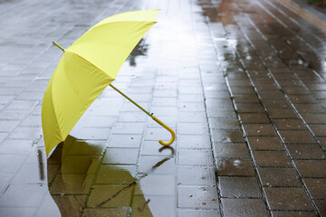 Yellow umbrella on wet asphalt outdoors, space for text