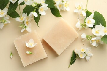 Soap bars and jasmine flowers on beige background, flat lay