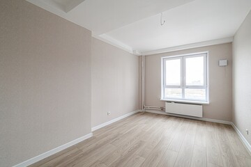 Empty room with beige walls, light wood floor, and a window. The room is bright and appears newly renovated or in the process of being finished