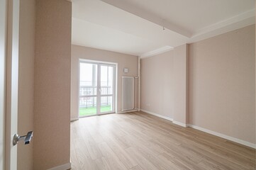 Bright empty room with wooden floor, beige walls and balcony
