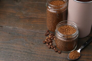 Instant coffee in jars and beans on wooden table, closeup. Space for text