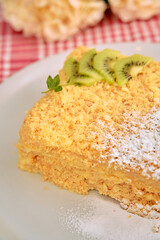 Delicious layered cake topped with kiwi on white plate
