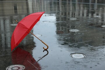 Red umbrella under heavy rain outdoors, space for text