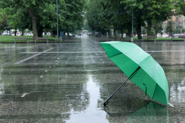 Green umbrella under heavy rain outdoors, space for text