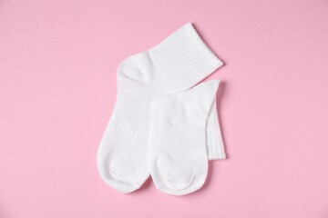 Pair of comfortable white socks on pink background, top view