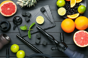 Hookah, coal and fresh fruits on black wooden table, flat lay