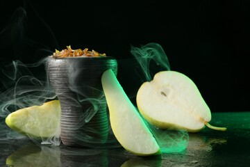 Hookah bowl with pear pieces and smoke on black table, closeup