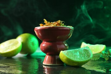 Hookah bowl with limes, mint and smoke on black table, closeup