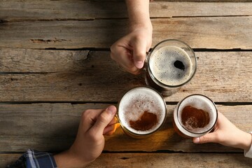 Friends with glasses of beer at wooden table, top view. Space for text