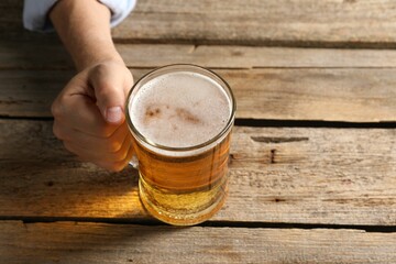 Man with glass mug of beer at wooden table, above view. Space for text