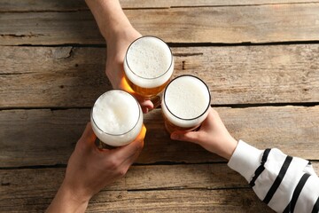 Friends with glasses of beer at wooden table, top view