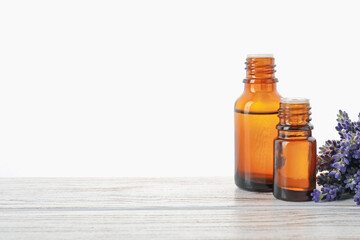 Natural essential oil and lavender flowers on wooden table against white background
