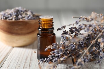Natural essential oil and lavender flowers on white wooden table, closeup