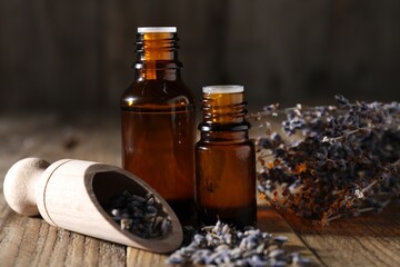 Natural essential oil and lavender flowers on wooden table, closeup