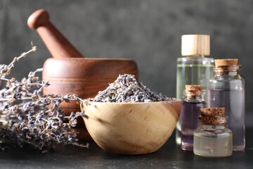 Natural essential oil and lavender flowers on black table, closeup