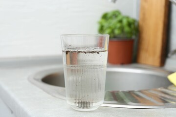 Glass with dirty water near sink indoors