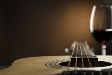 Acoustic guitar and glass of red wine on black background, closeup. Space for text