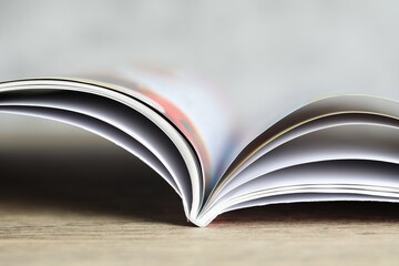 One open magazine on wooden table, closeup