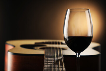 Acoustic guitar and glass of red wine on black background, closeup. Space for text
