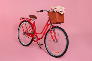 Bicycle with basket of beautiful flowers on pink background