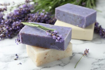 Soap bars and lavender flowers on white marble table, closeup