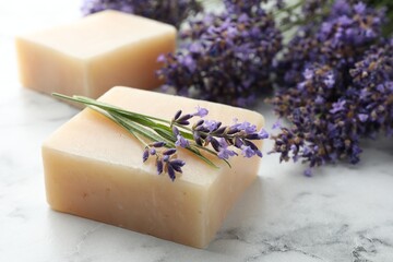 Soap bars and lavender flowers on white marble table, closeup