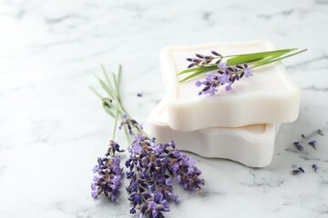 Soap bars and lavender flowers on white marble table, closeup. Space for text