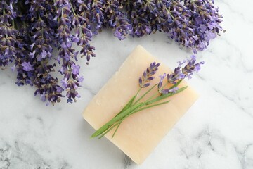 Soap bar and lavender flowers on white marble table, flat lay