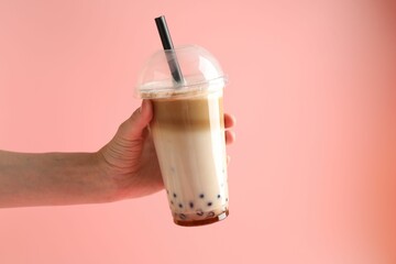 Woman with tasty milk bubble tea on pink background, closeup