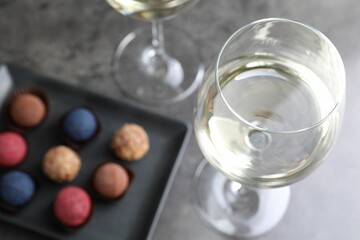 Tasty wine in glasses and truffle bonbons on grey table, above view