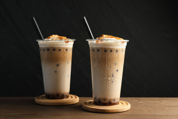 Tasty milk bubble tea in plastic cups on wooden table