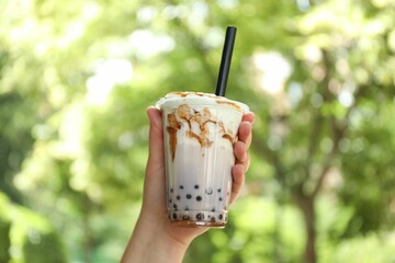 Woman with tasty milk bubble tea in plastic cup outdoors, closeup