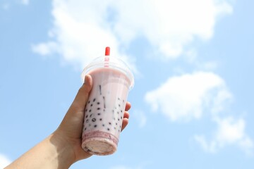 Woman with tasty milk bubble tea in plastic cup outdoors, closeup. Space for text