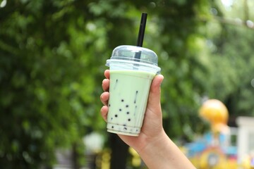 Woman with tasty milk bubble tea in plastic cup outdoors, closeup