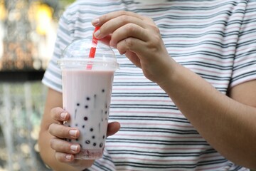 Woman with tasty milk bubble tea in plastic cup outdoors, closeup