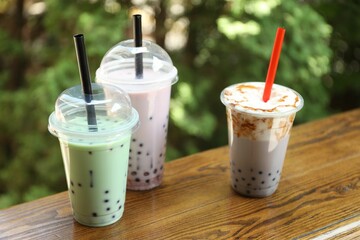 Tasty milk bubble tea in plastic cups on wooden table