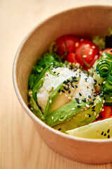 Fresh sushi bowl with rice, avocado, cherry tomatoes, and cucumber in brown container