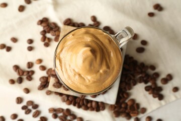 Delicious dalgona coffee in glass cup and beans on table, flat lay