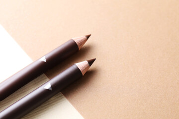 Different eyebrow pencils on beige background, closeup. Space for text