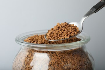 Taking instant coffee with spoon on grey background, closeup