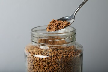 Taking instant coffee with spoon on grey background, closeup