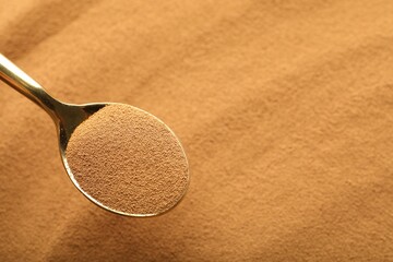 Spoon with aromatic instant coffee as background, closeup