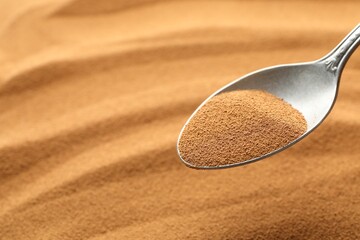 Spoon with aromatic instant coffee as background, closeup