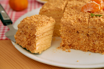 Delicious honey cake with crumbly layers and mandarin garnish